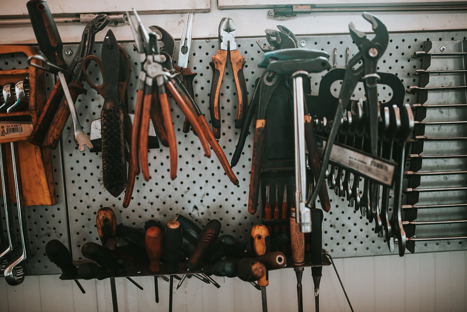 Pliers, wrenches and screwdrivers hanging on a pegboard in a workshop